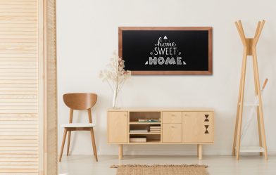 Wooden cabinet with flowers and heather between stylish brown chair and wooden hanger, real photo